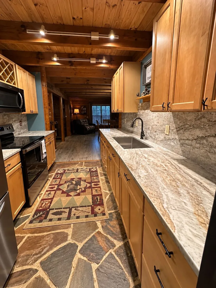 Cabin kitchen with wood cabinets, stone floor and counters